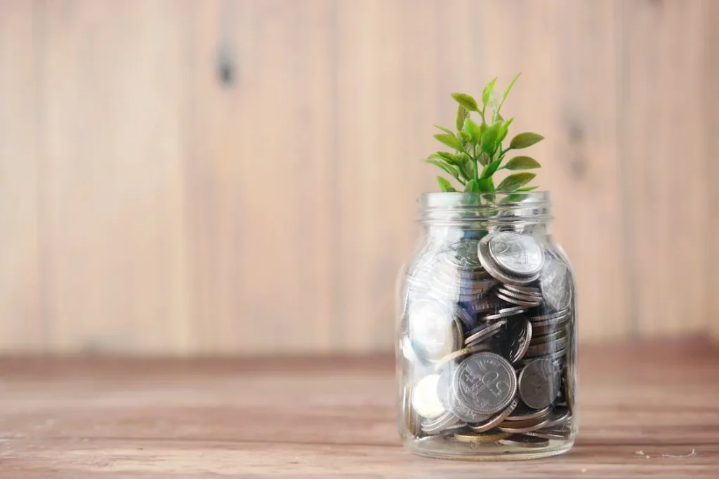 Top Ways to Save Money and Build Wealth Over Time 9 Saving money and building wealth concept with plant in jar
